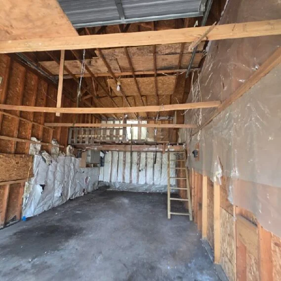 Junk removal service in progress showing a partially cleared residential garage or storage space with debris and materials staged for removal.