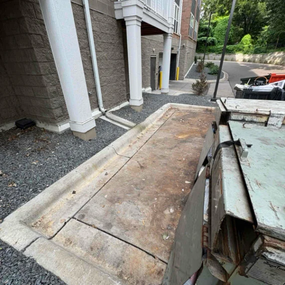 Junk removal service in progress showing old wooden doors and metal debris being loaded into a truck bed at a residential property entrance.