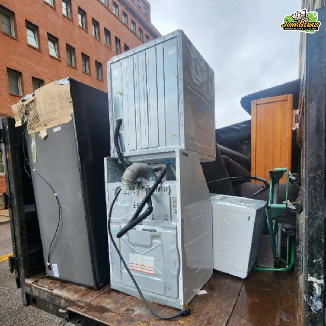 Junk removal service in progress showing discarded appliances and electronics awaiting pickup in an urban alley.