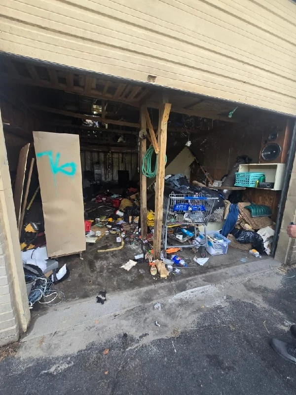 Junk removal service in progress showing a cluttered garage filled with accumulated debris, clutter, and miscellaneous items before clearance.