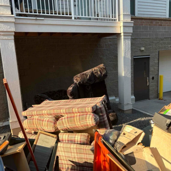 Junk removal service in progress showing furniture and household items being cleared from a residential garage space.
