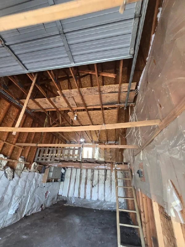 Junk removal service in progress showing a partially demolished interior space with debris, exposed framing, and cleared materials ready for disposal.