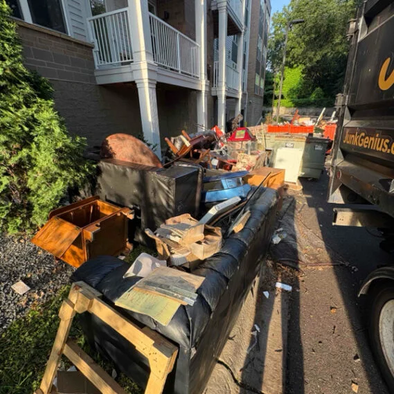 Junk removal service in progress with multiple dumpsters and debris being loaded during a residential property cleanup.