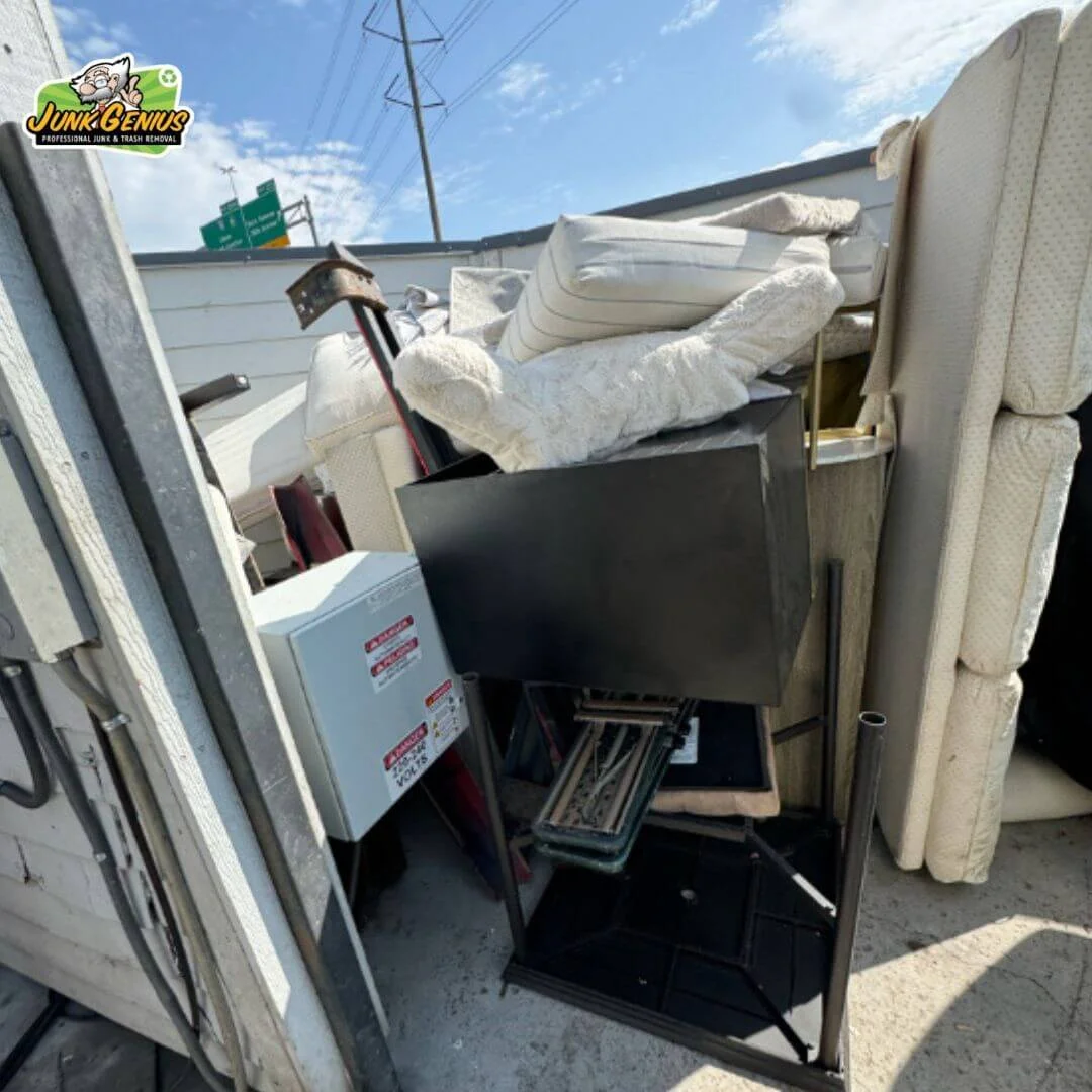 Junk removal service in progress, with a full truck bed loaded with furniture, mattresses, and household items being hauled away.