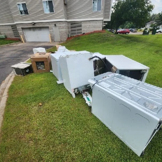 Junk removal service showing disposed appliances and household items collected on a residential lawn.