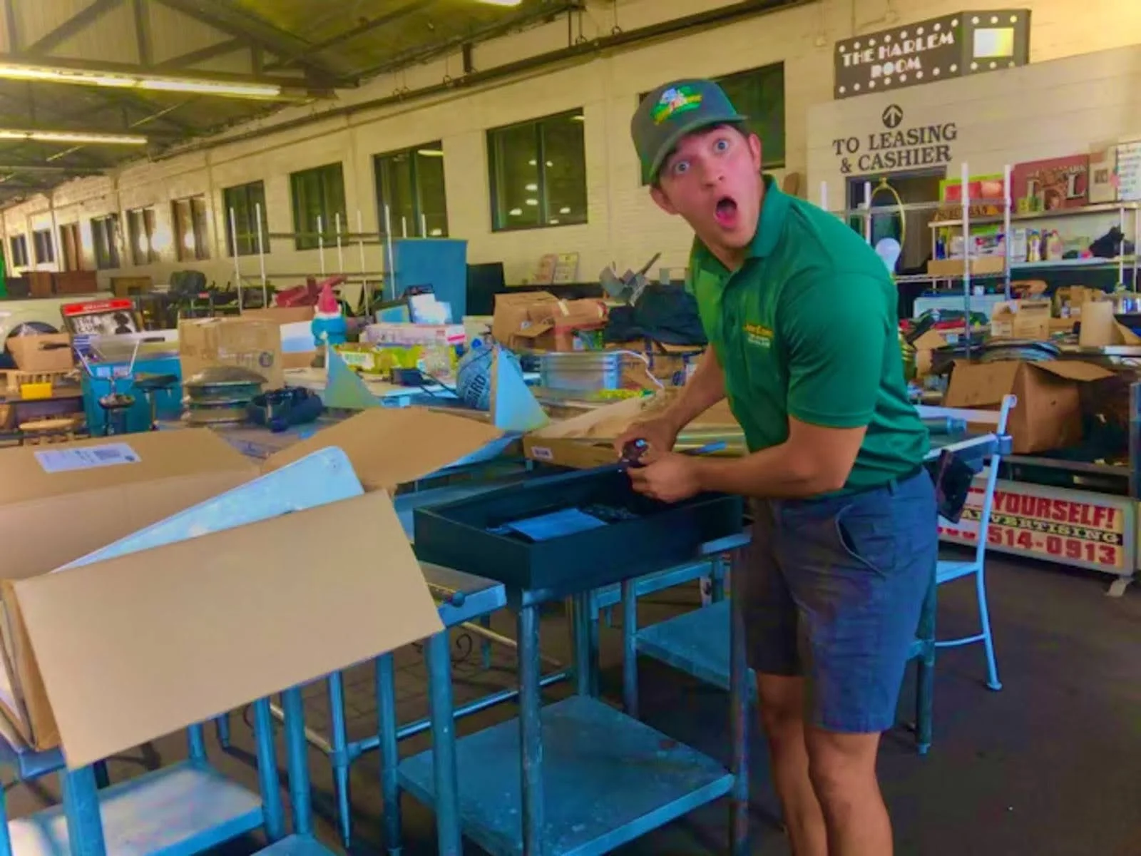 A person demonstrating DIY junk removal and cardboard recycling in a warehouse or community space filled with boxes and materials.