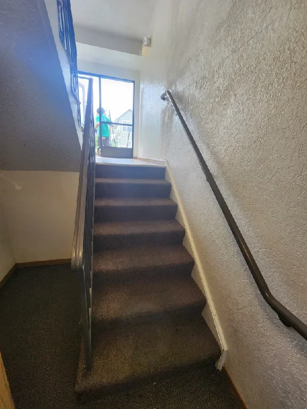 A residential stairwell interior showing an empty hallway and stairs, which does not depict junk removal work or services.