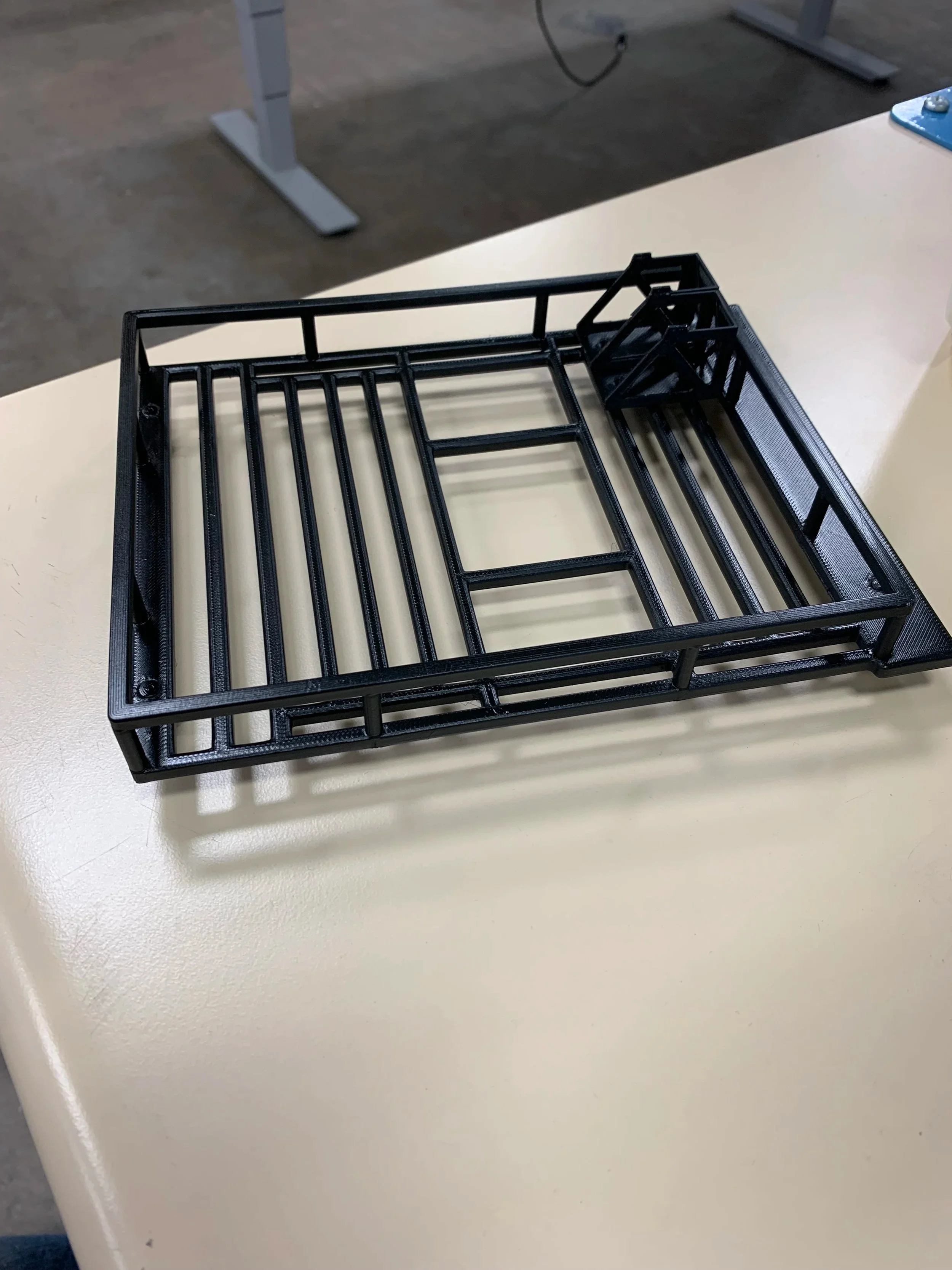 Black metal roof rack basket with organizational dividers on a white display table in a showroom setting.