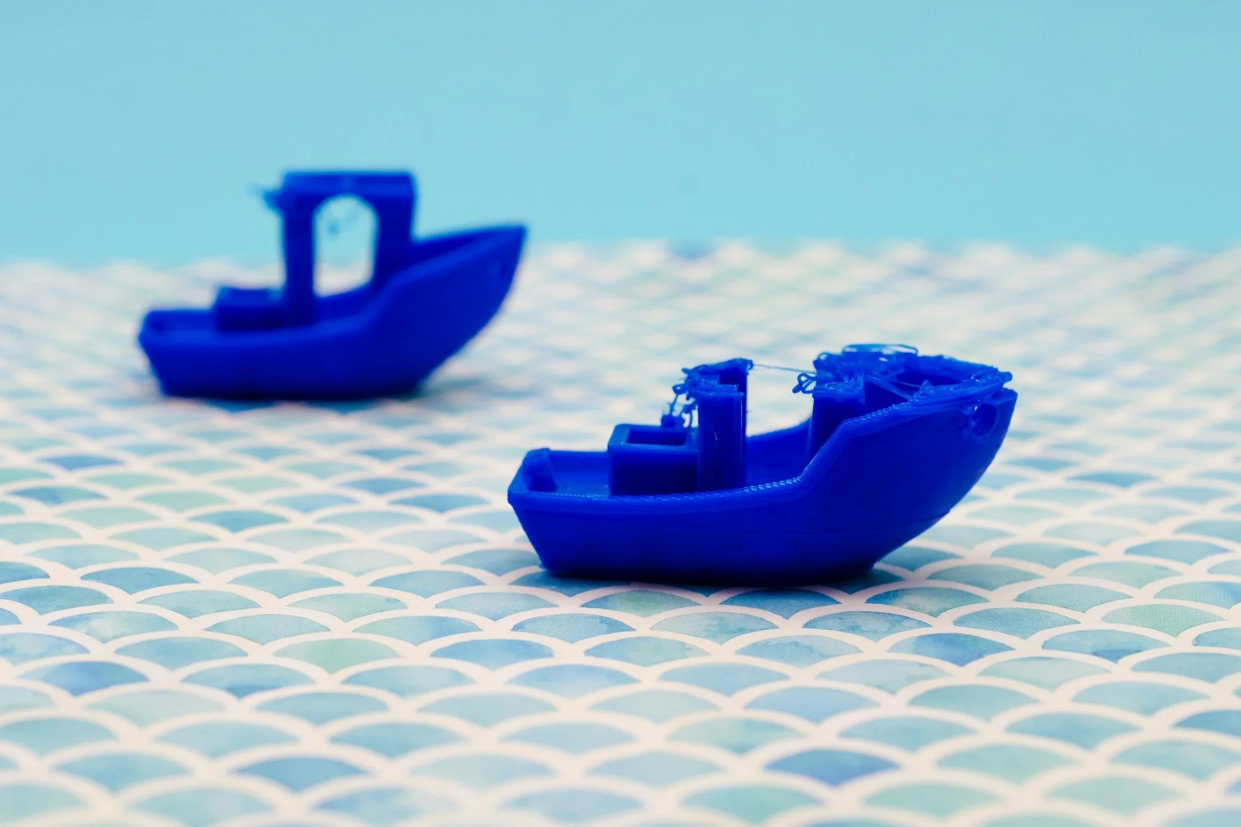 Blue toy boats on a light blue and white wave-patterned surface in a decorative arrangement