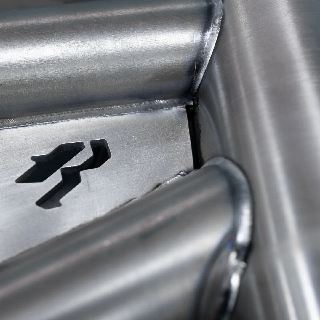 Close-up detail of a metallic roller shade or window blind mechanism showing the branded insignia and cylindrical tube assembly.