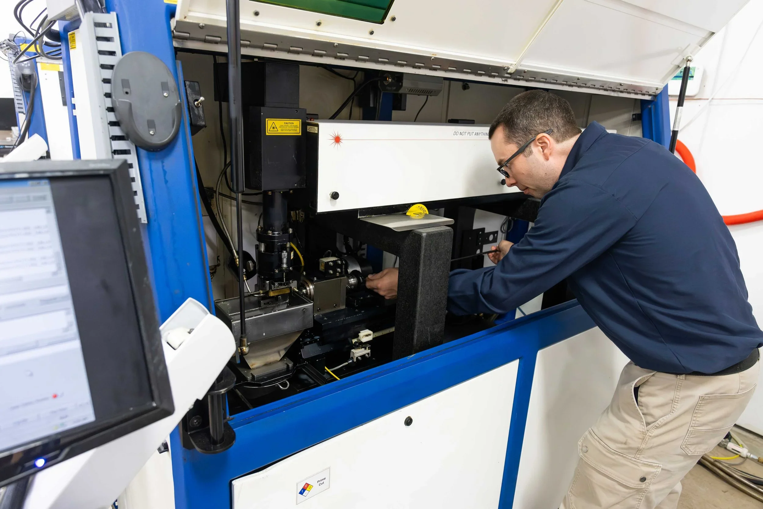 Industrial laser cutting or engraving machine being operated by a technician in a manufacturing facility.