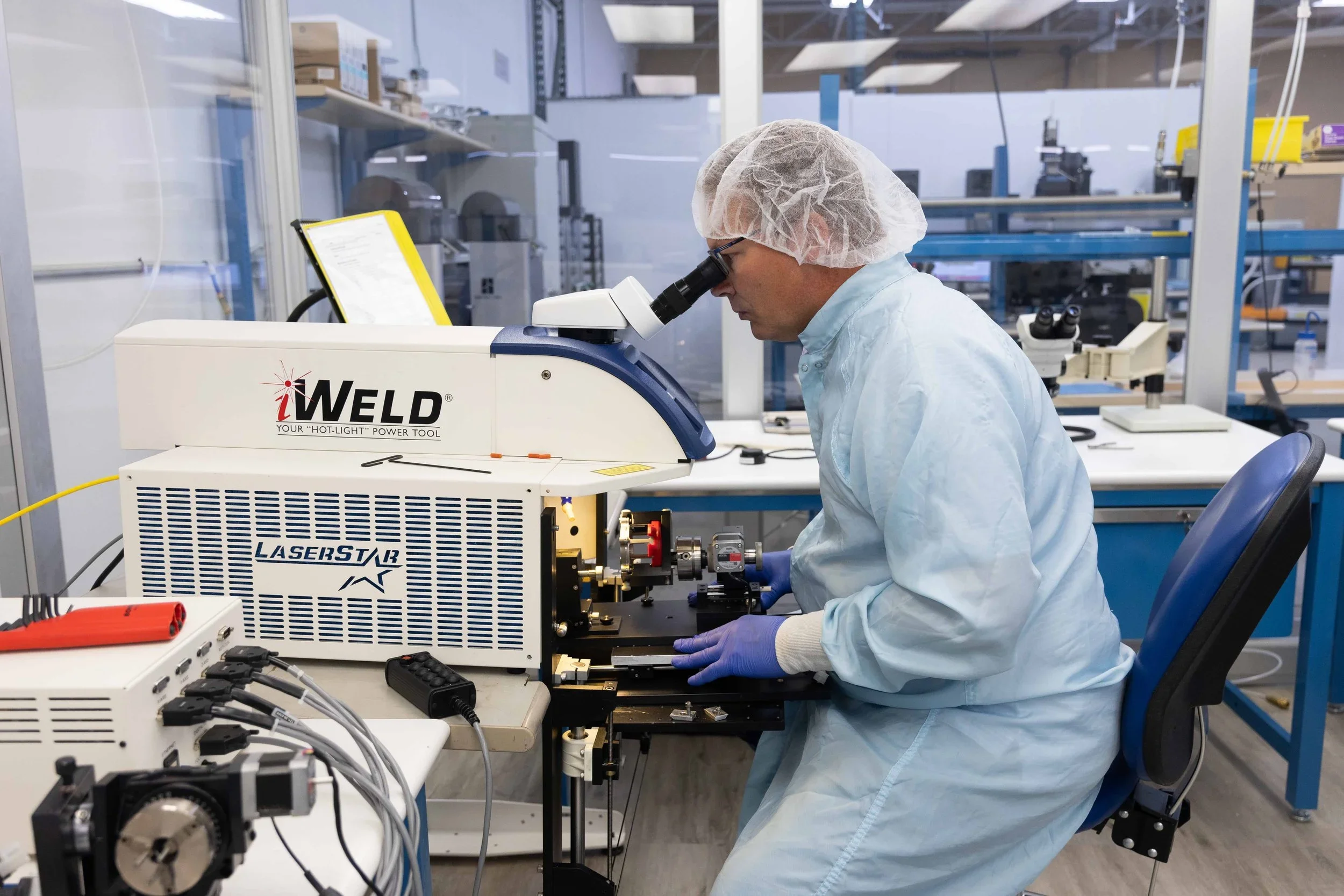 A LaserStar welding system being inspected and serviced by a technician in a cleanroom laboratory setting.