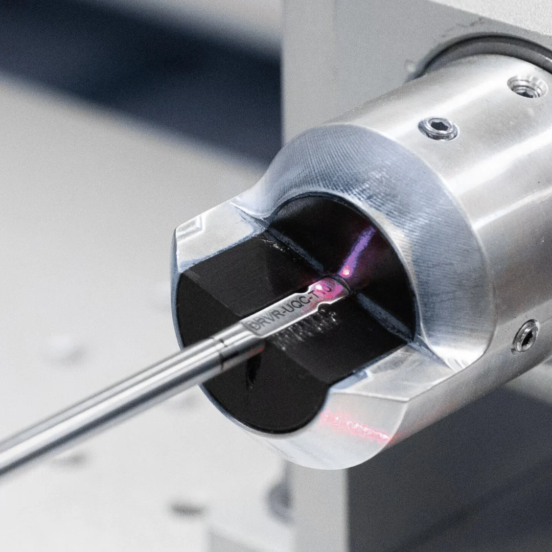 Motorized roller shade mechanism with cord and pink control indicator being installed on a white cylindrical roller tube.