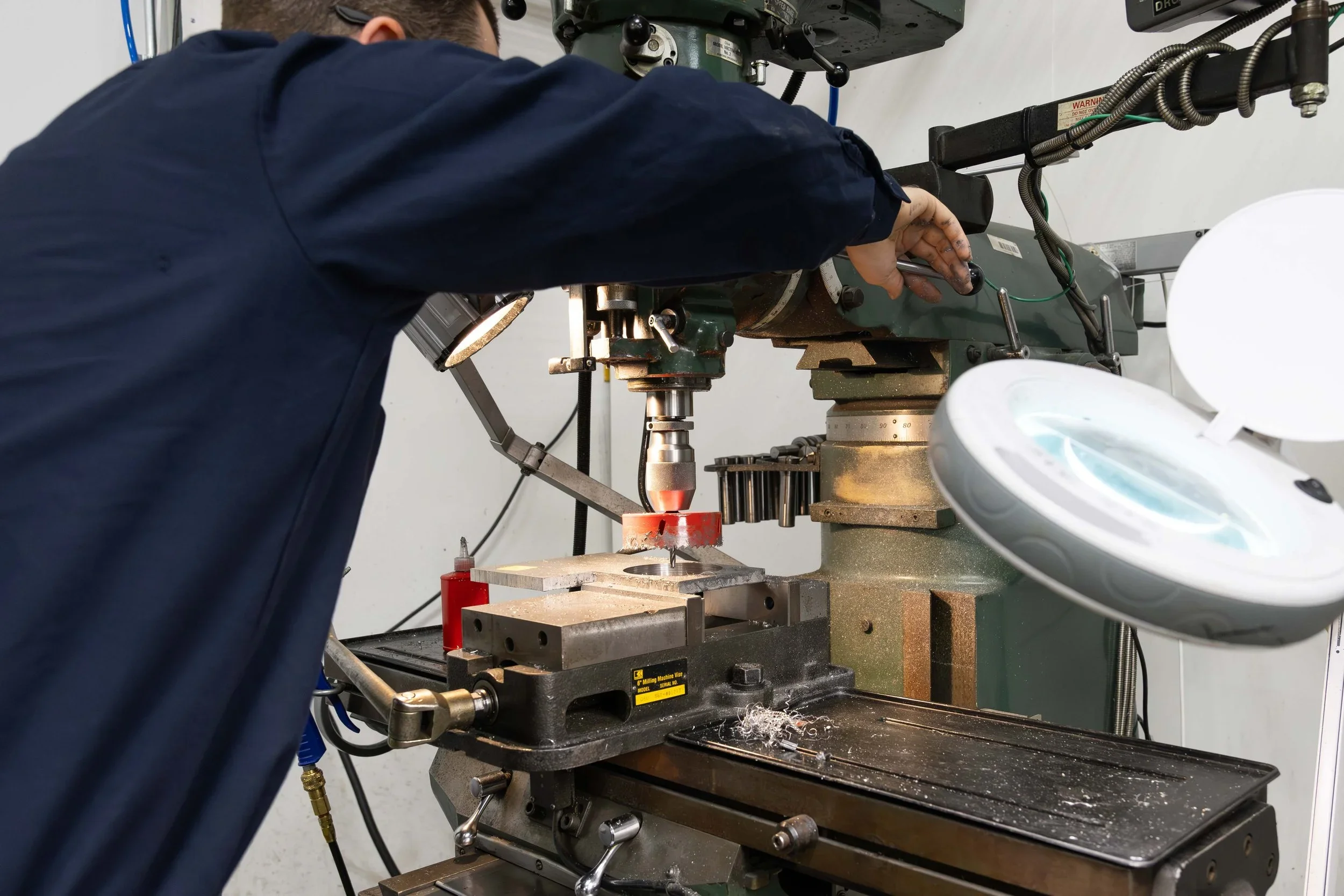 A precision drilling machine being operated by a technician in a industrial workshop setting.