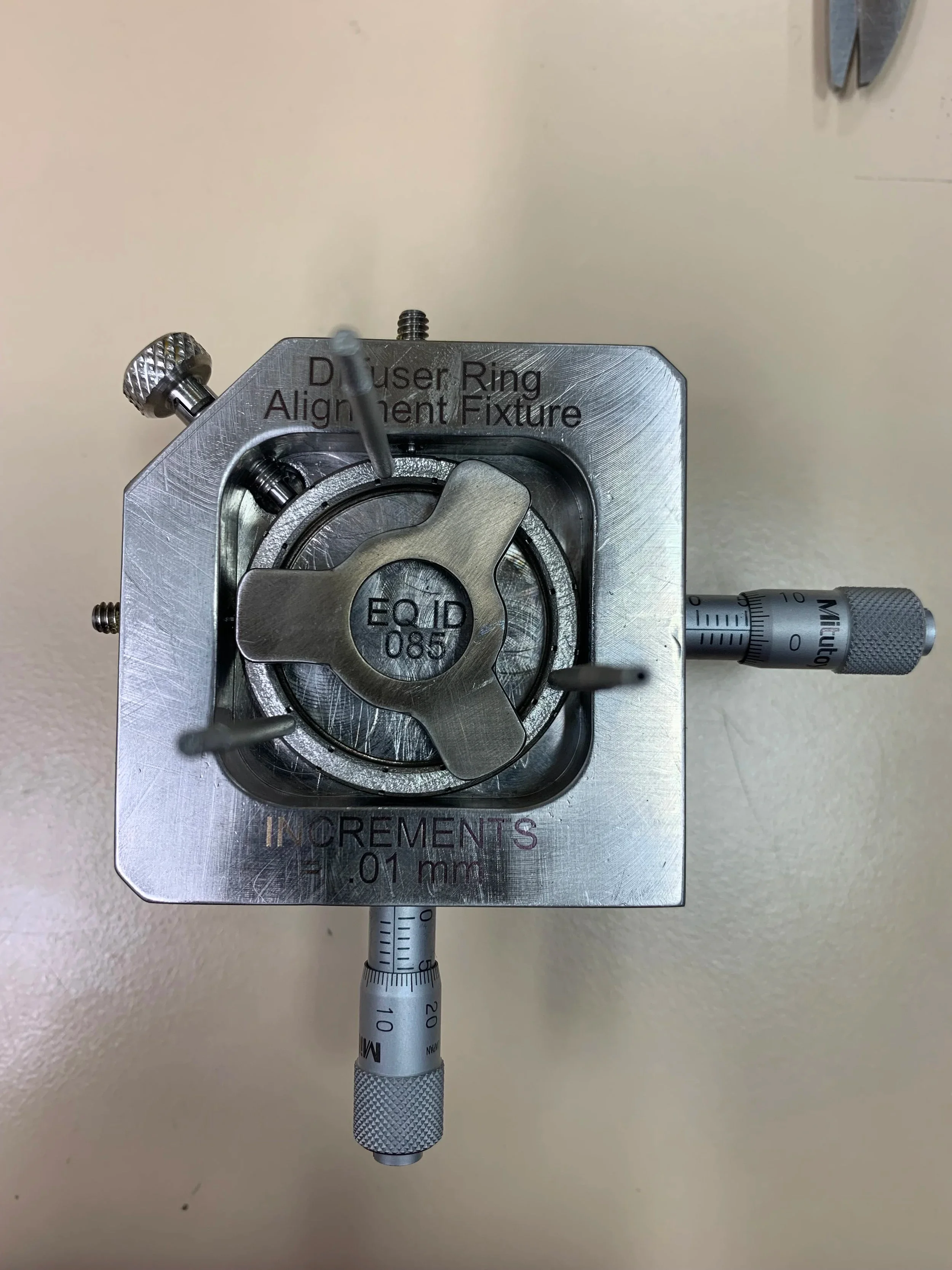 A precision ring alignment fixture with micrometer adjustments mounted on a metallic base used for optical or measurement calibration work.