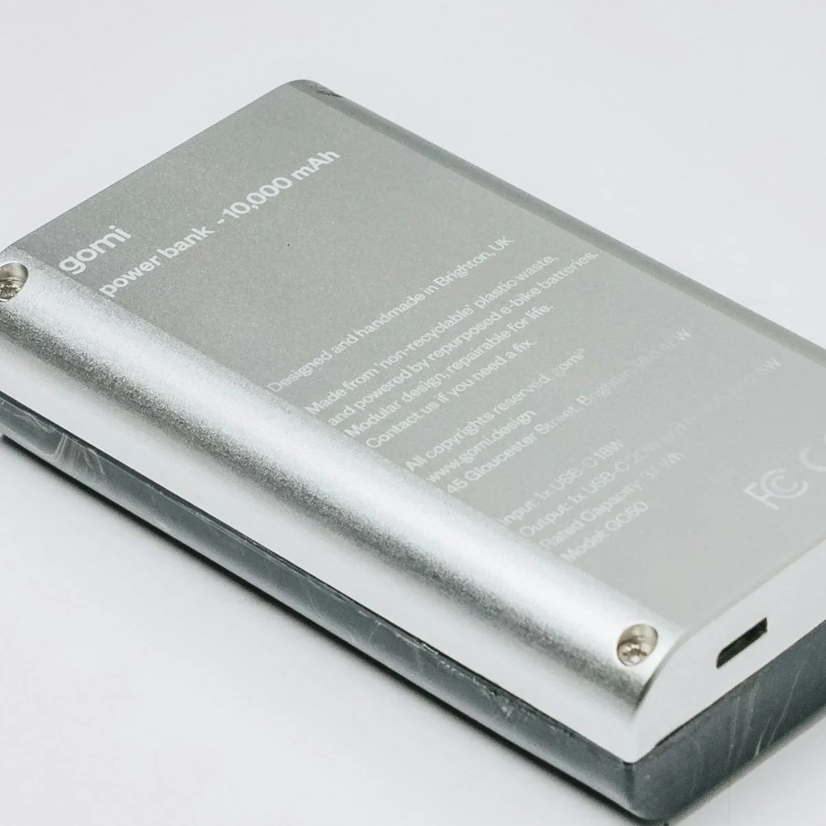 Silver aluminum power bank with 10,000 mAh capacity displayed at an angle on a white background
