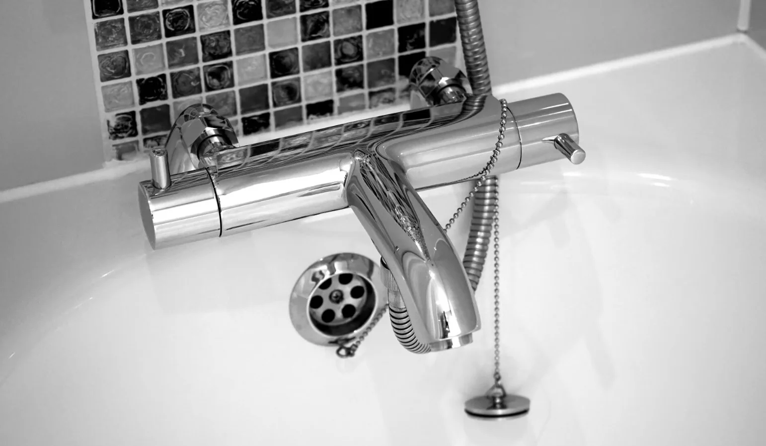 Chrome thermostatic tub faucet with a handheld shower and tub drain