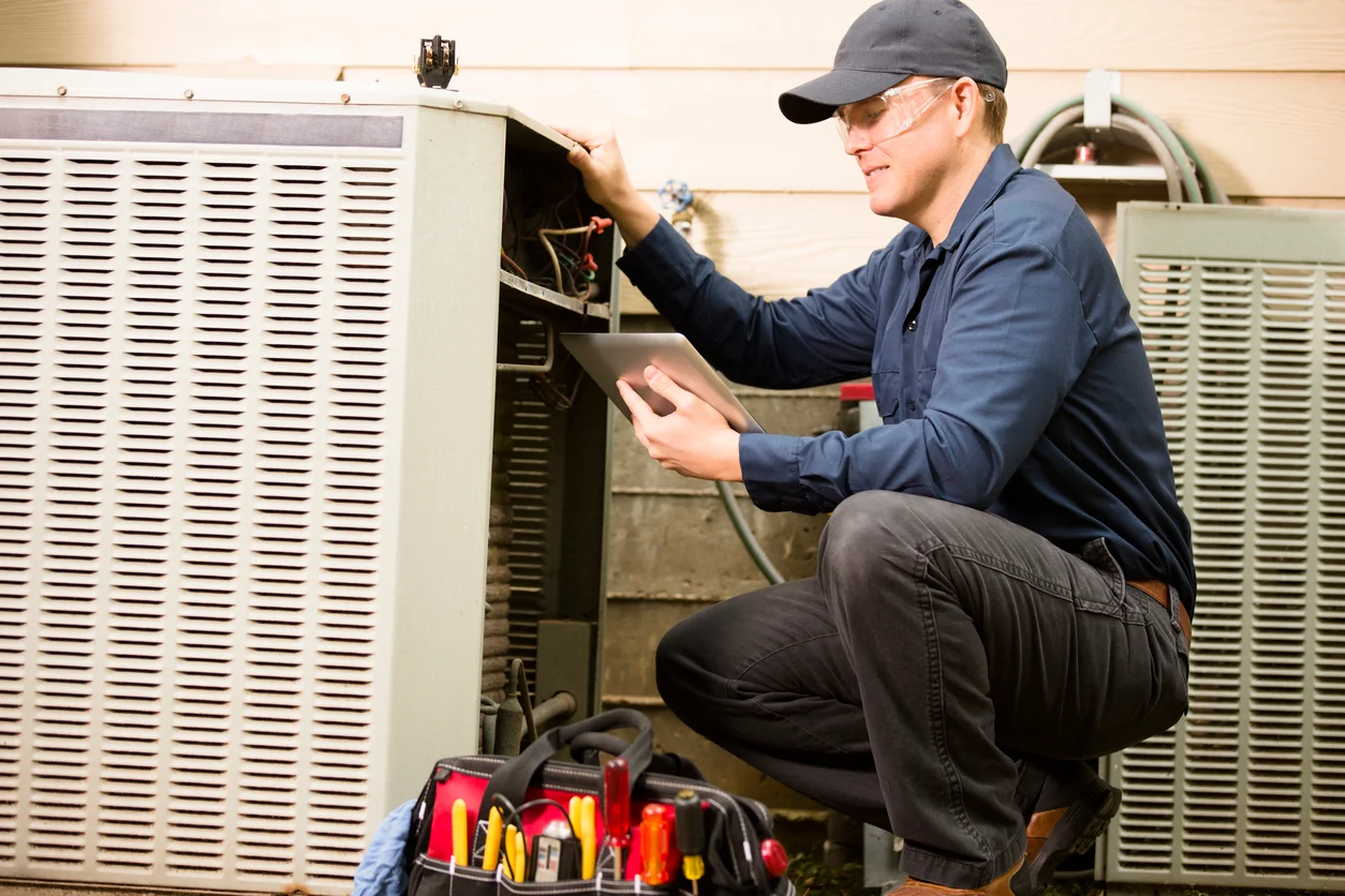 HVAC technician servicing an outdoor air conditioner condenser