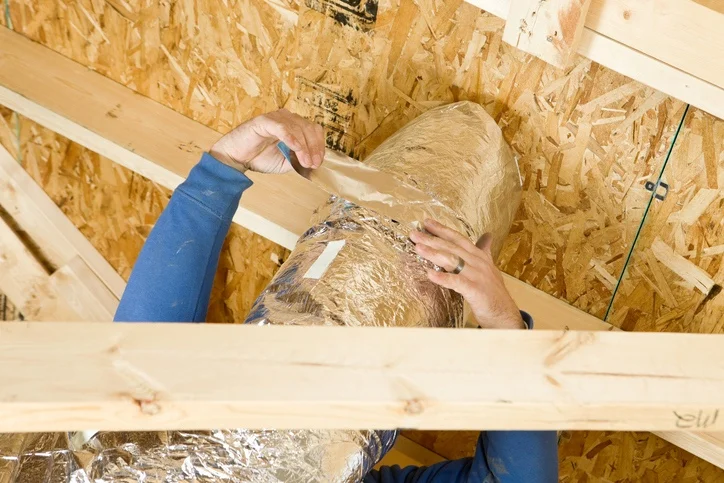Foam insulation being fitted around a water pipe inside a framed wall