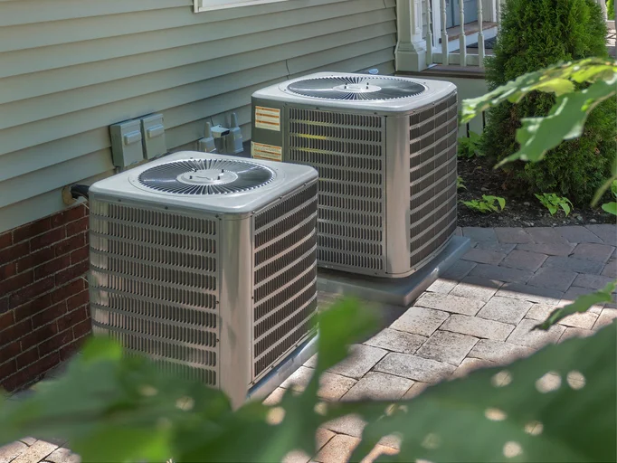 Two air conditioner condensers outside a home