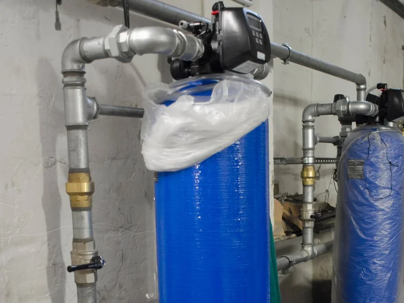 Water softener and filtration system installation with dual tanks and digital control valve in a basement utility space.