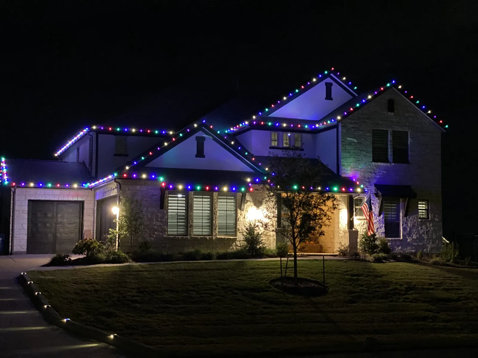 Two-story home with colored holiday lights on the rooflines