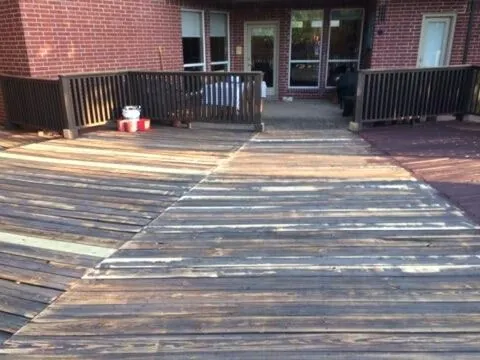 Stained deck behind a red brick home