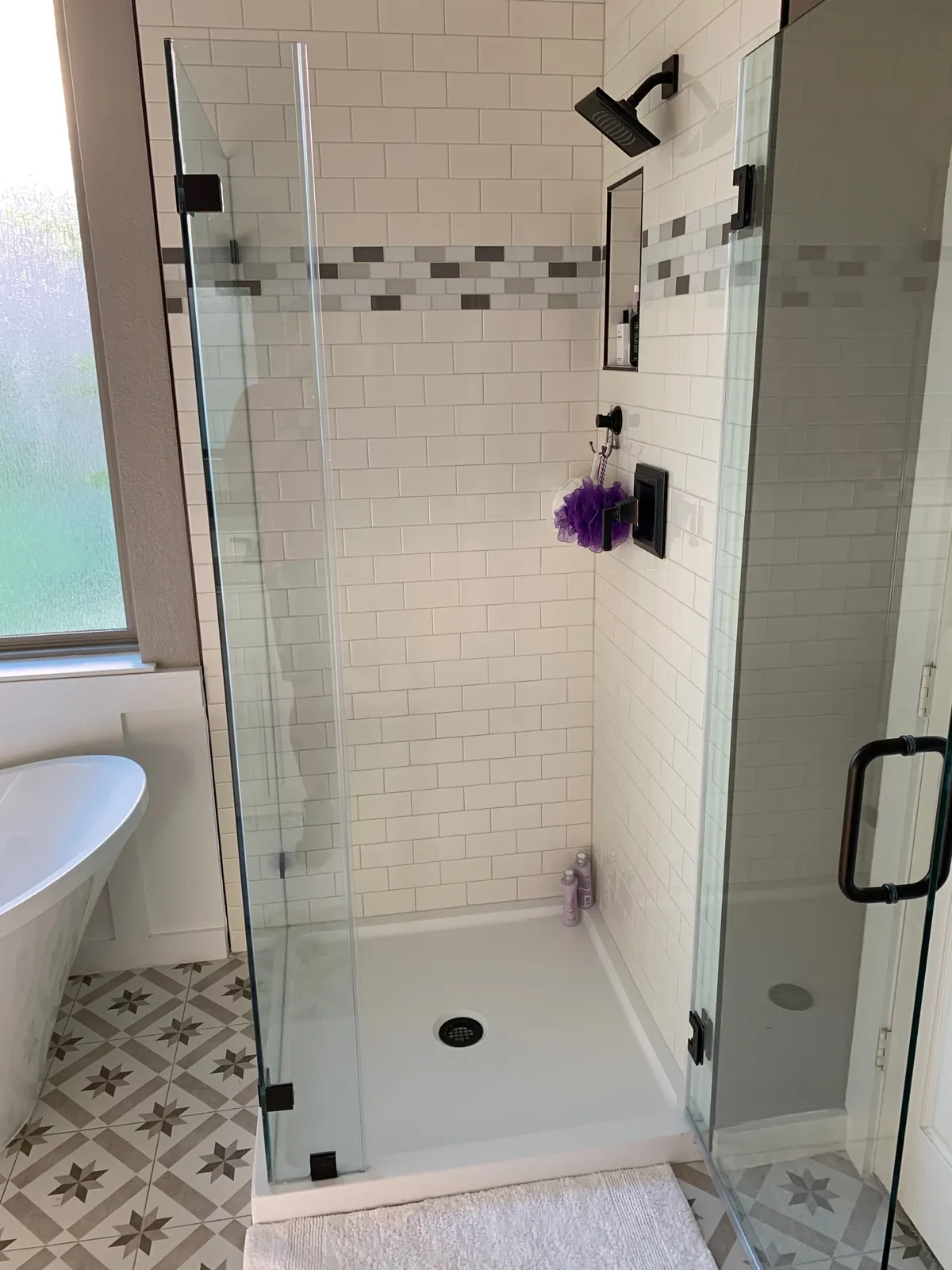 Glass shower with subway tile and a patterned floor