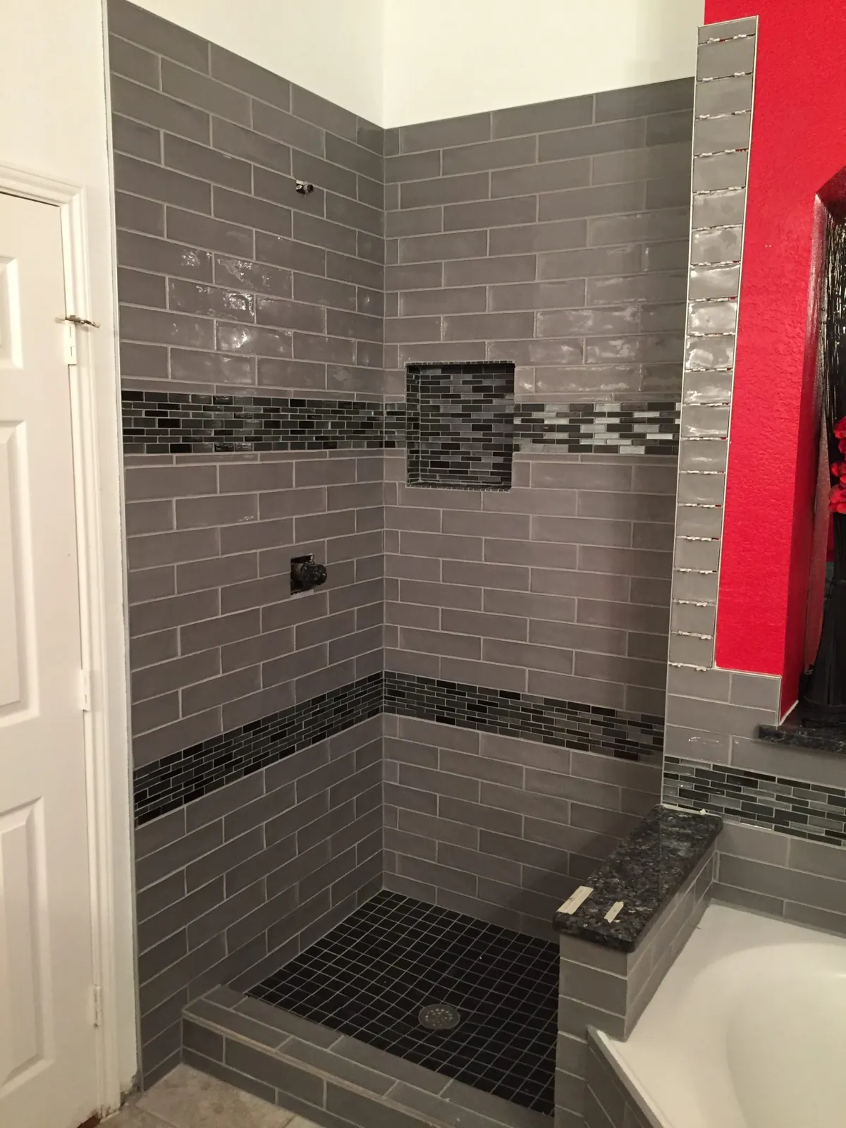 Gray subway tile shower with a mosaic band