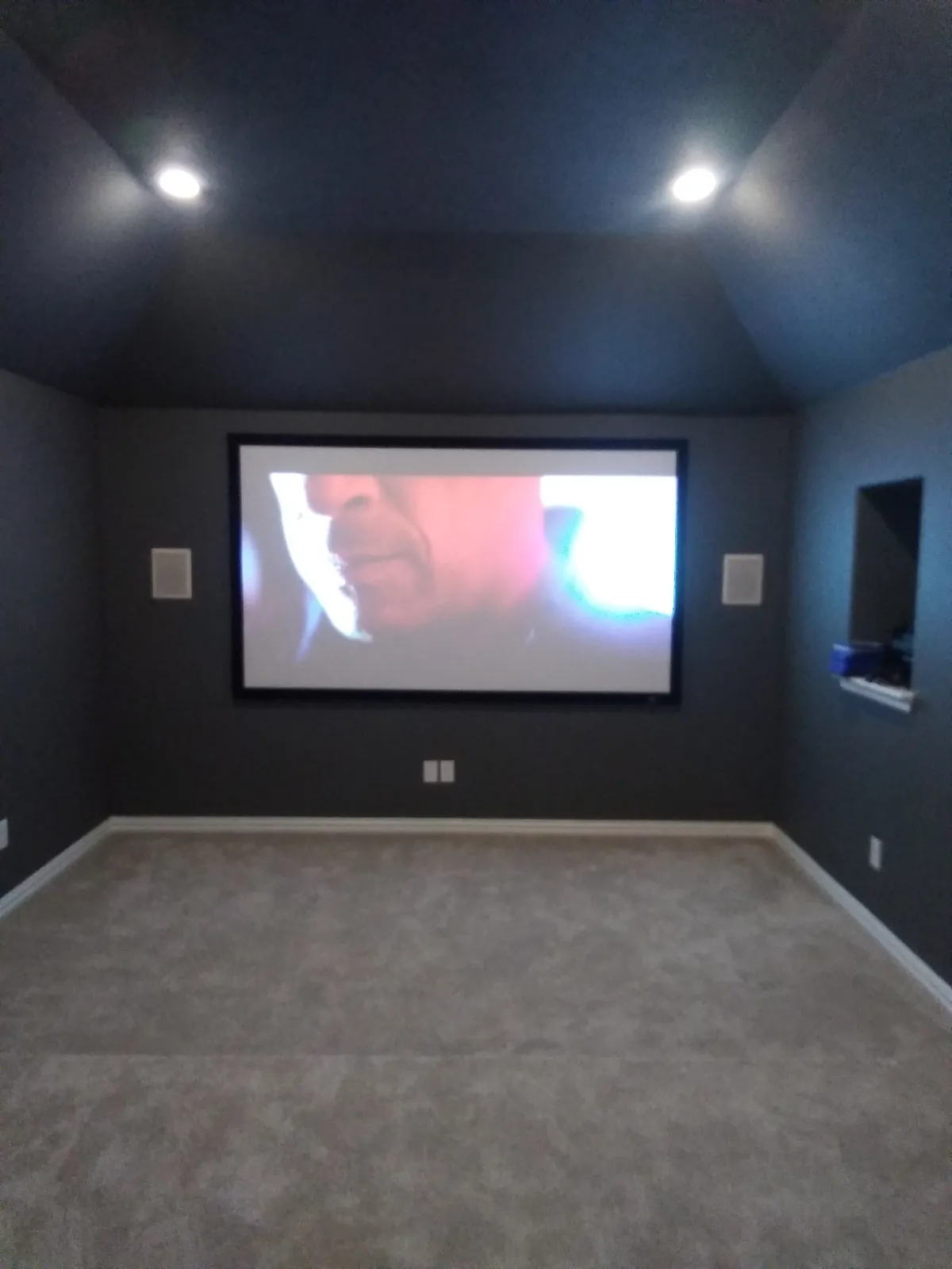 Dark painted home theater room with a projector screen