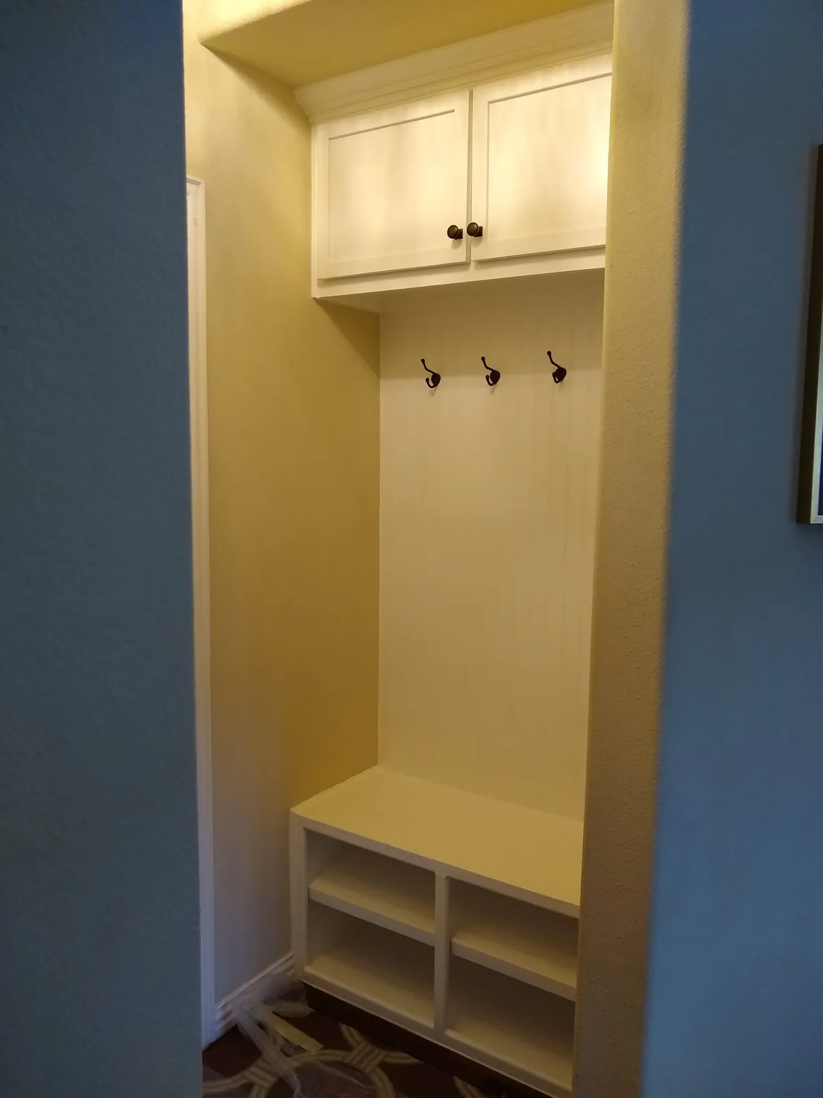 Built-in mudroom bench with hooks and an upper cabinet