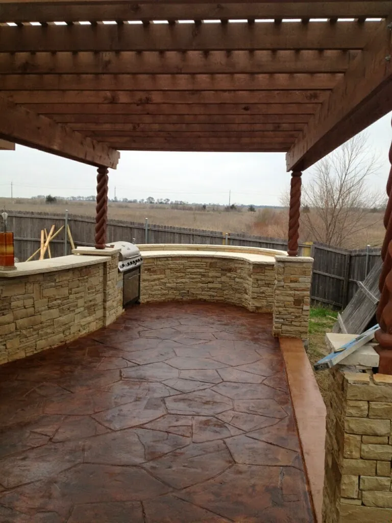 Pergola over a stone outdoor kitchen and patio
