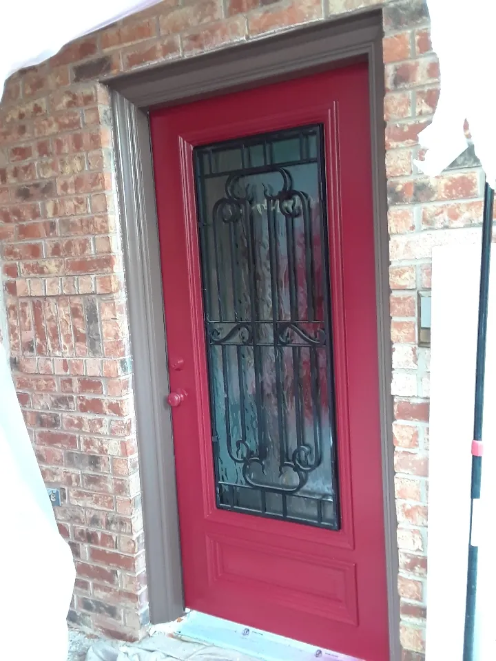 Front door painted red in a brick entry