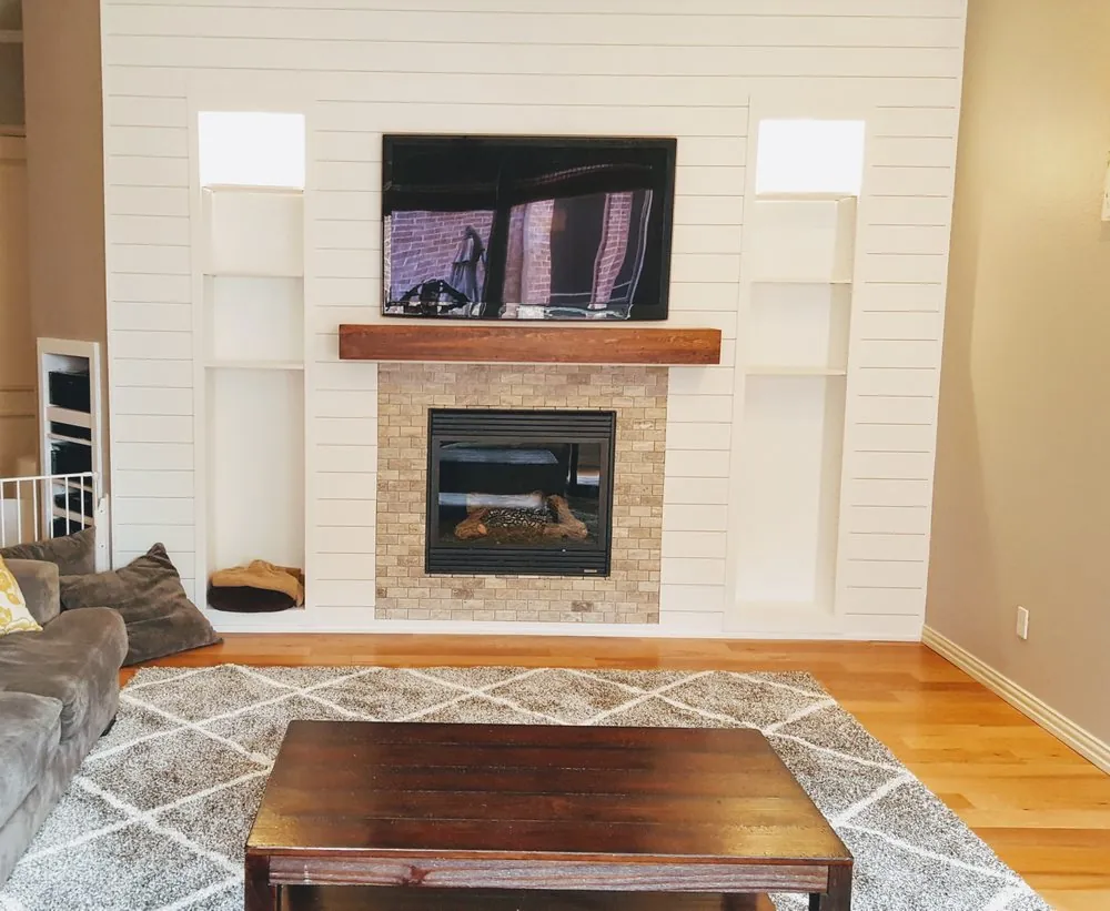 Shiplap fireplace surround with a wood mantel