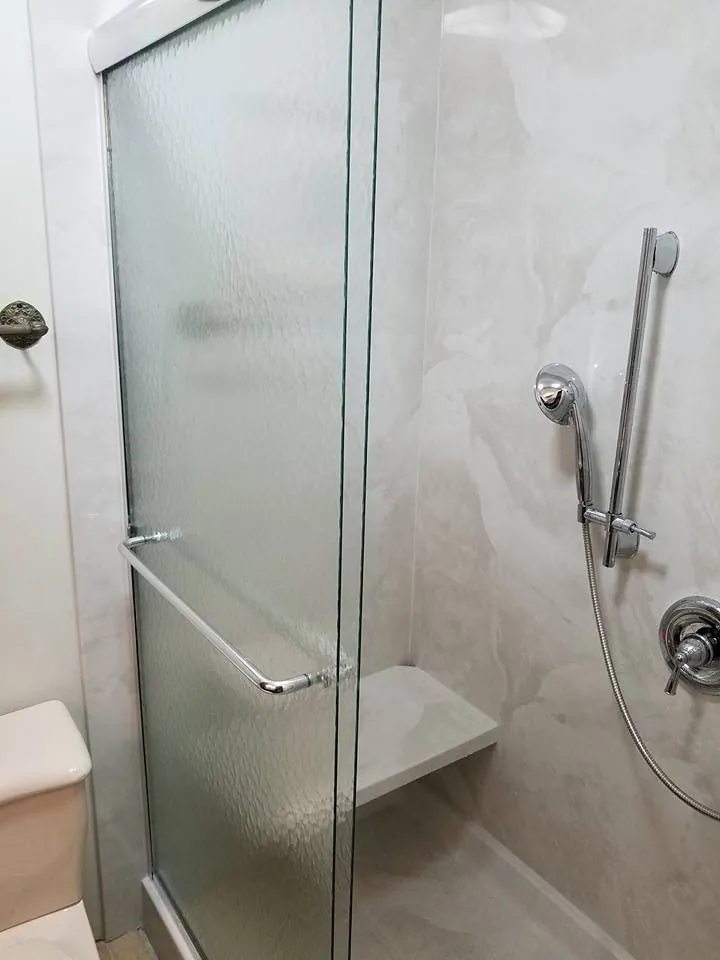 Glass shower with a grab bar and hand shower