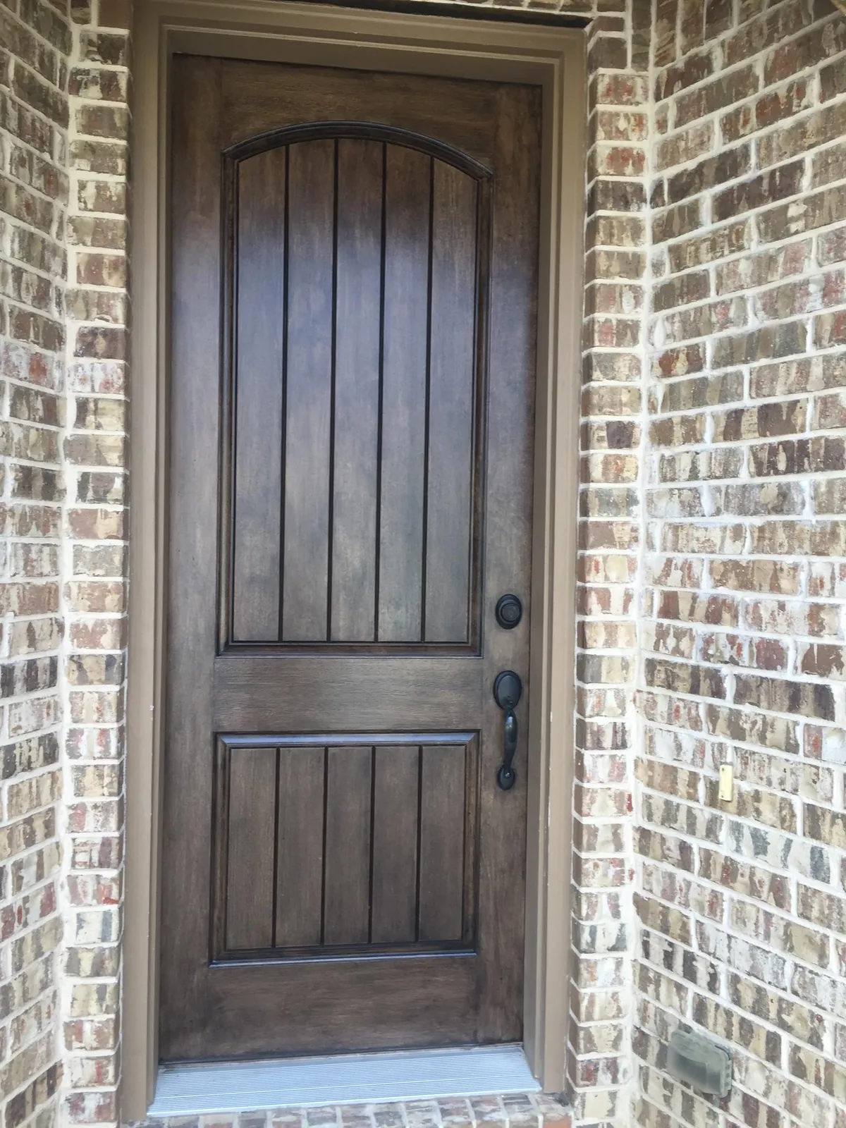 Refinished wood front door in a brick entry