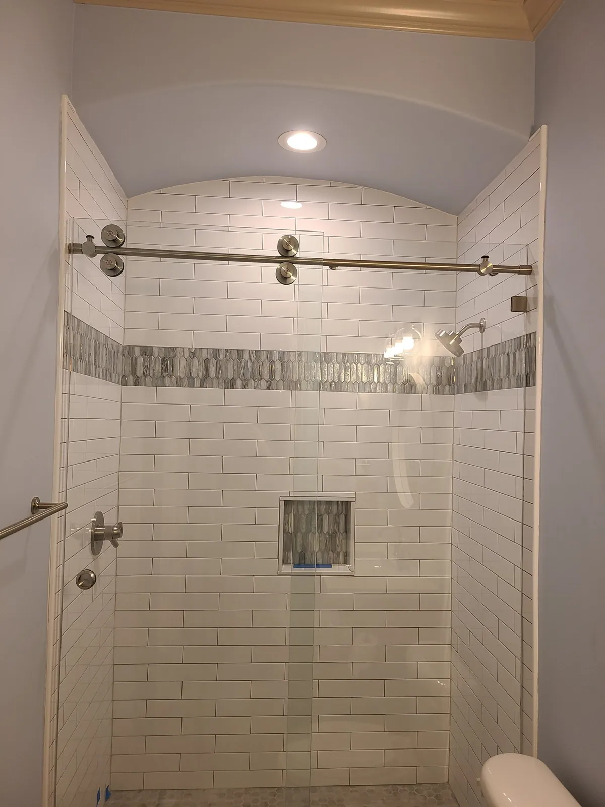 Subway tile shower with a niche and sliding glass door