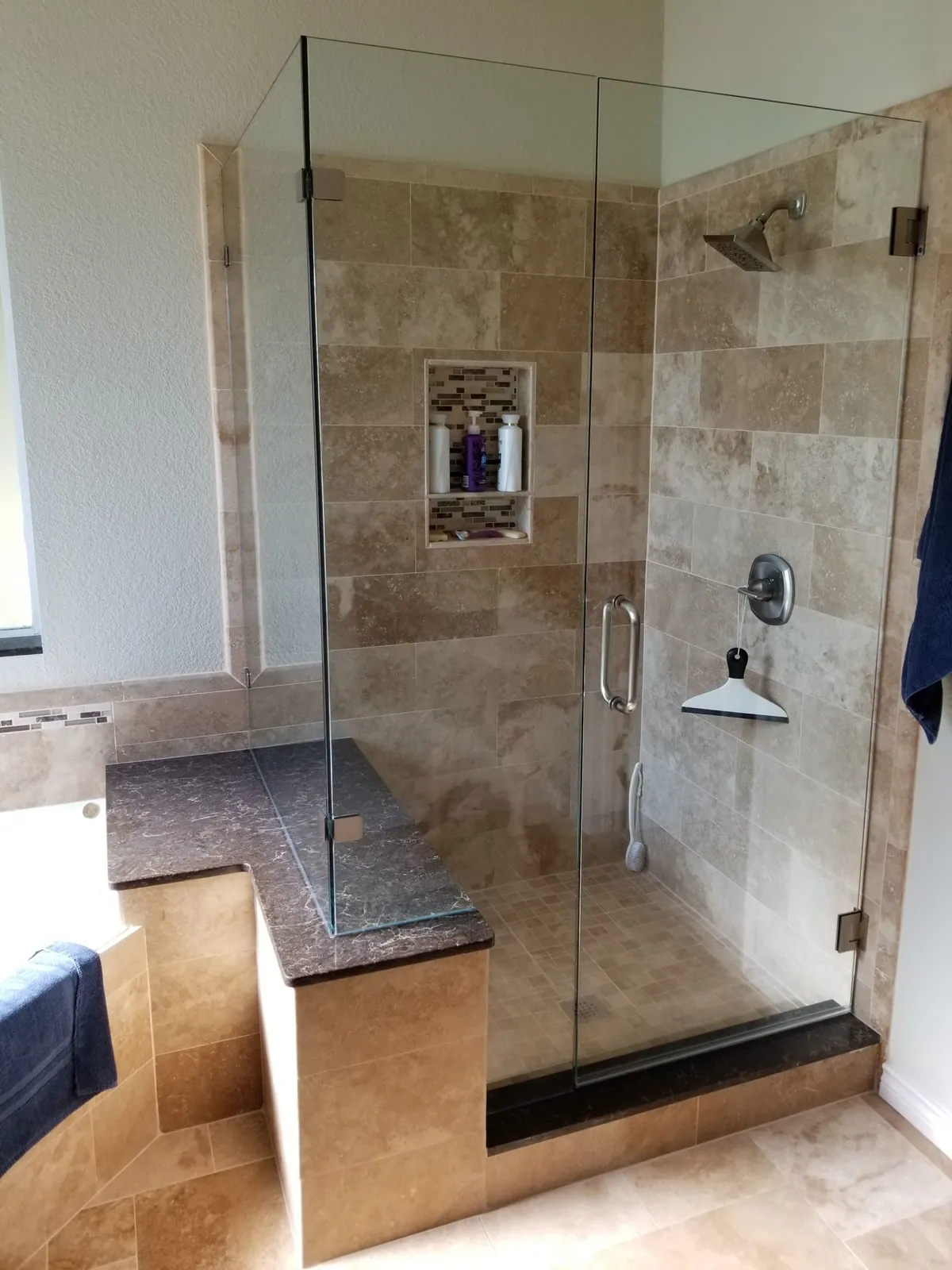Travertine shower with a frameless glass door