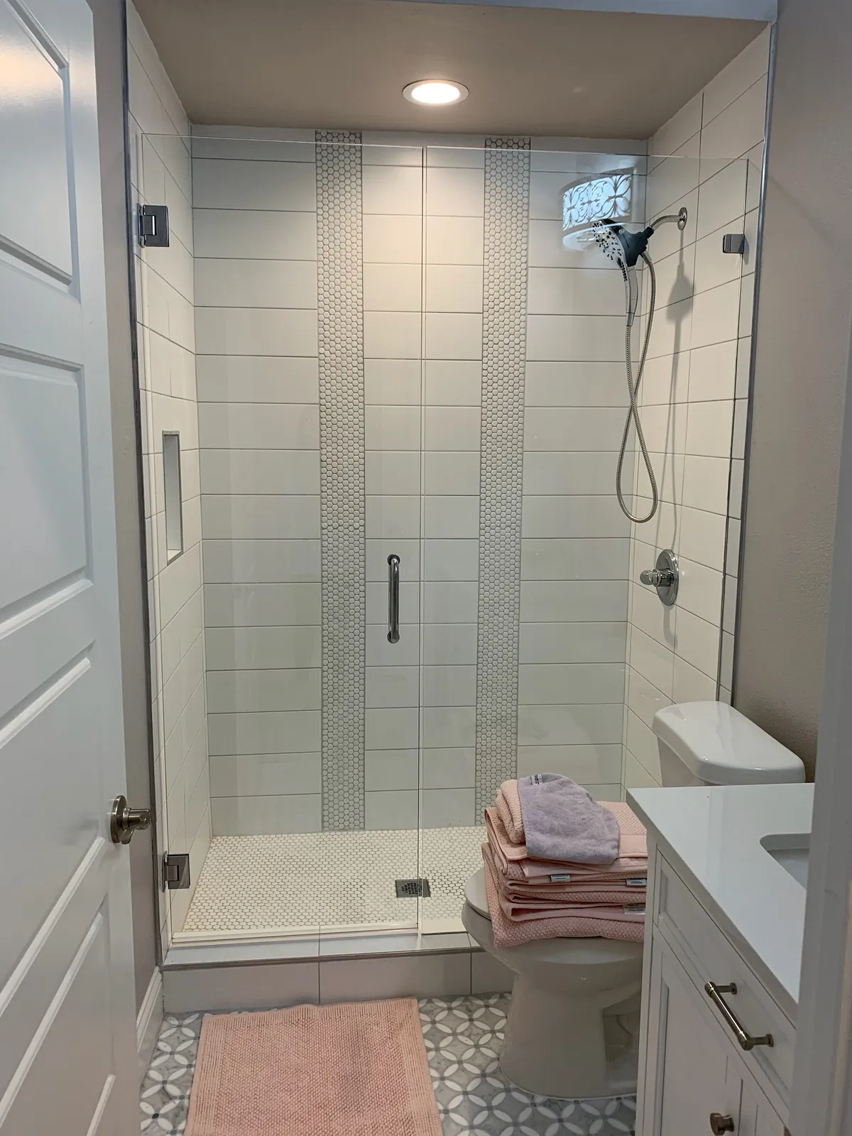 White tile walk-in shower with a glass door