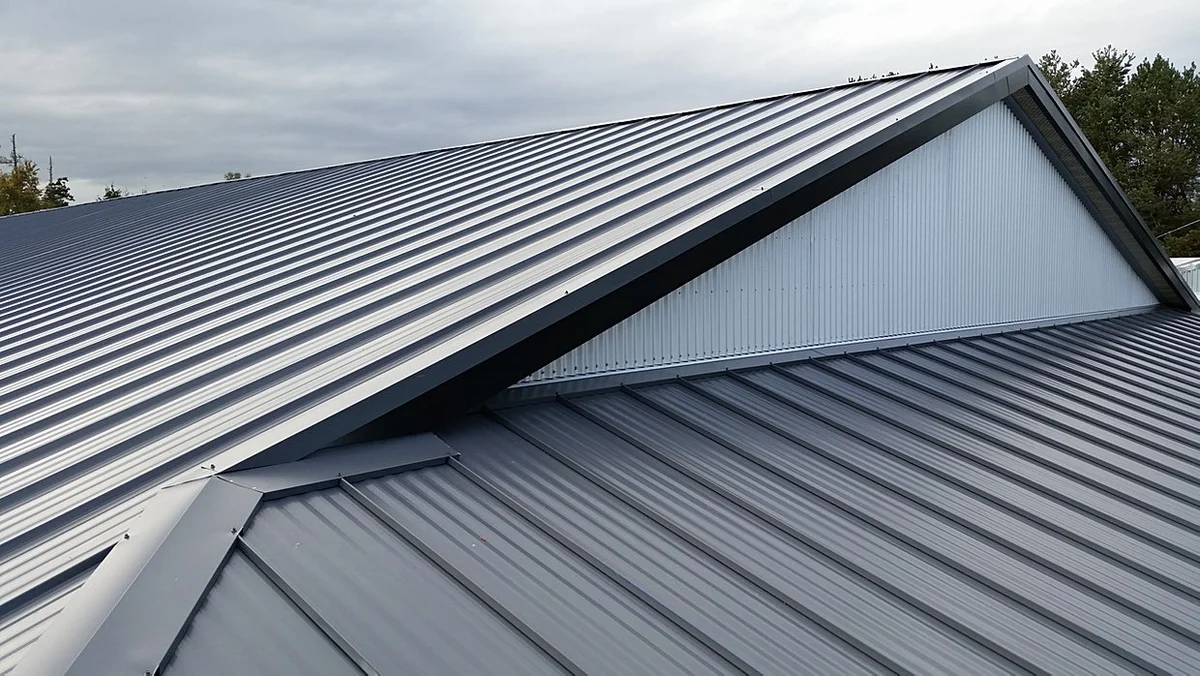 Metal roof installation featuring standing seam panels and a gabled roof structure on a residential building.