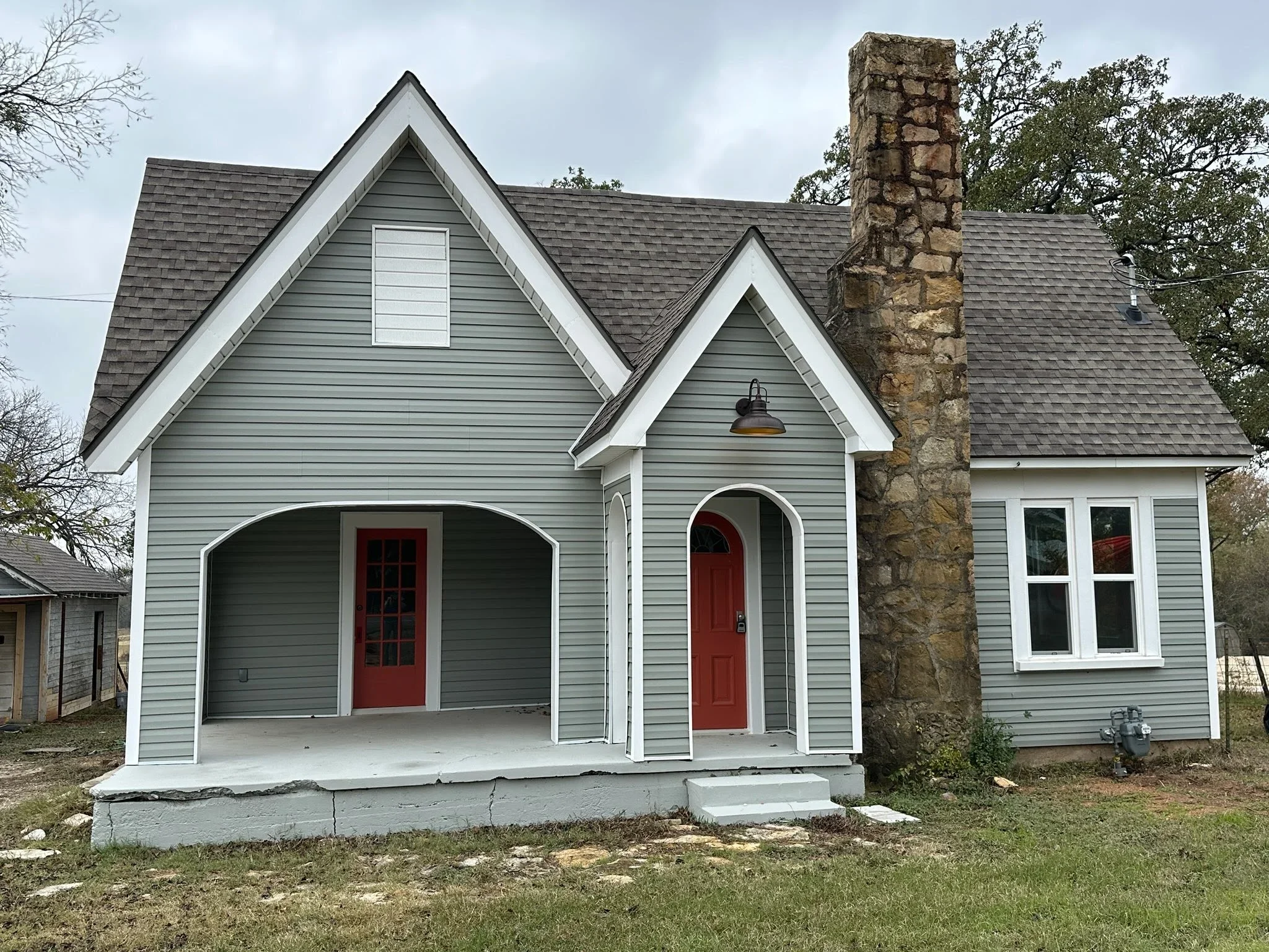 A residential home exterior featuring a newly installed roof with asphalt shingles and a stone chimney.