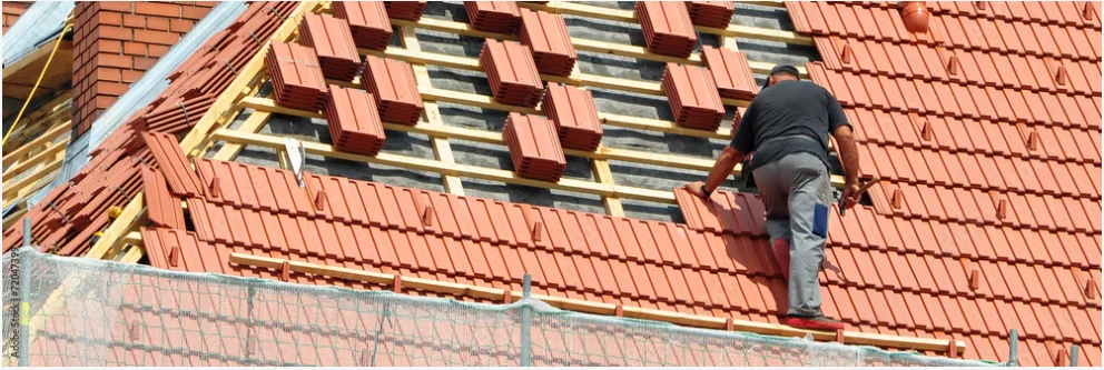 Roof installation work being performed on a residential property with red clay tiles and dormer windows visible.