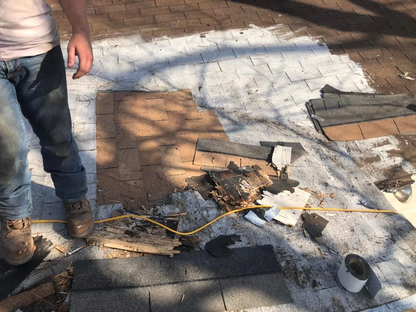 Roof shingle removal and replacement in progress on a residential asphalt shingle roof.
