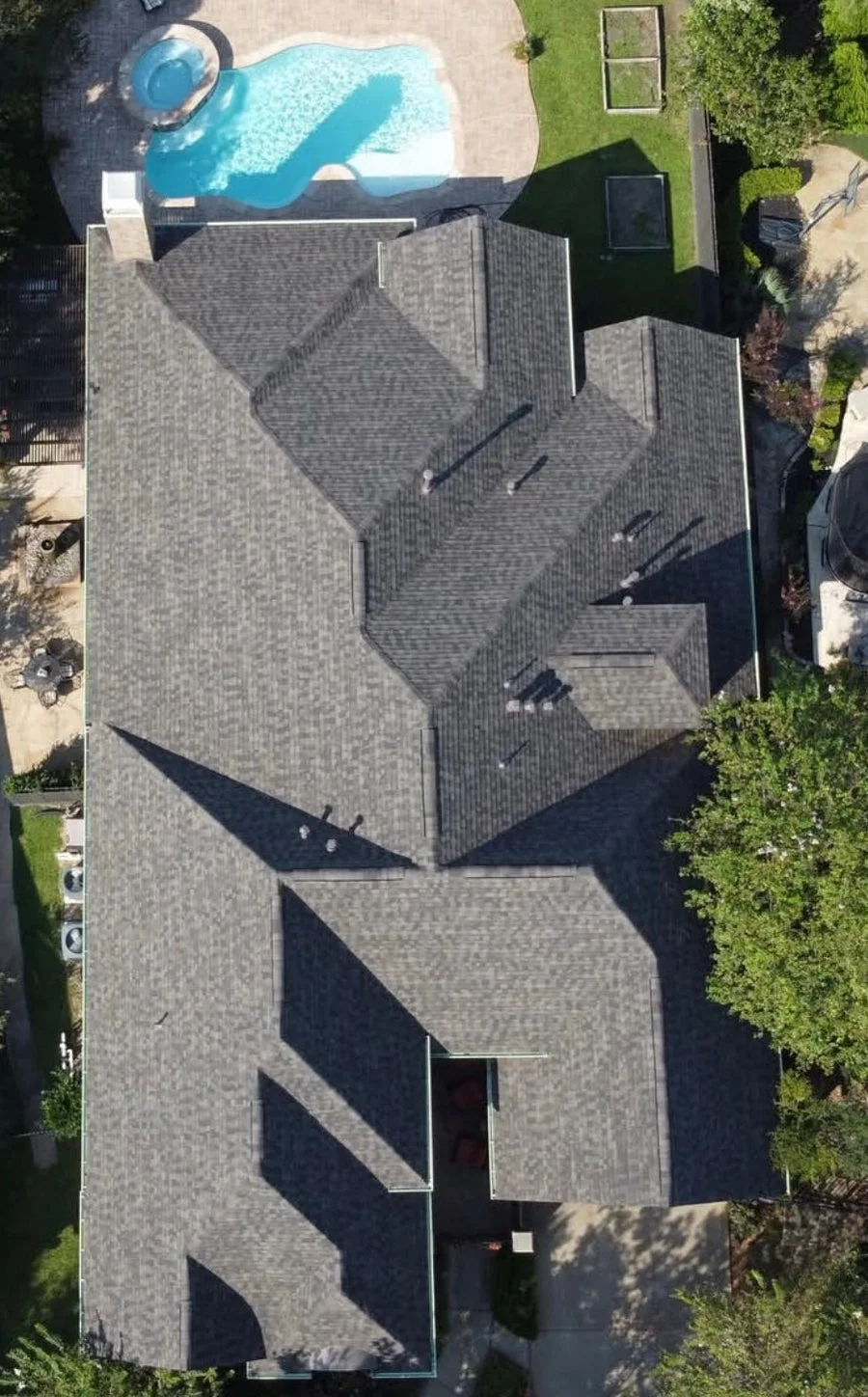 Completed asphalt shingle roof installation on a residential home with multi-peaked gable design, viewed from an aerial perspective.
