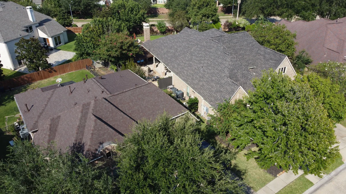 Completed asphalt shingle roofing installations on residential homes in a suburban neighborhood.