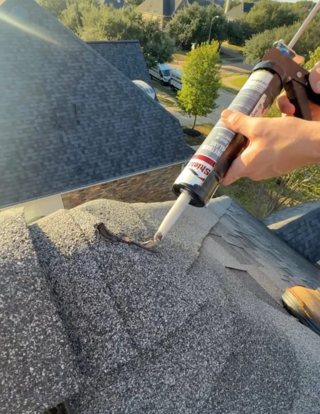 Roof sealant being applied to a asphalt shingle roof edge during maintenance work on a residential home.