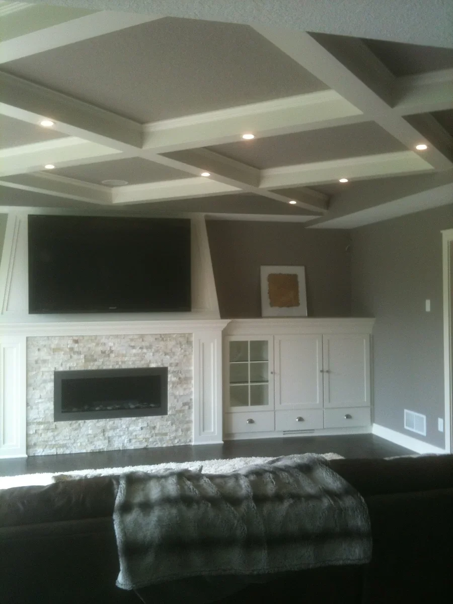 Custom built-in cabinetry with glass doors and a linear fireplace accent in a modern living room with coffered ceiling.