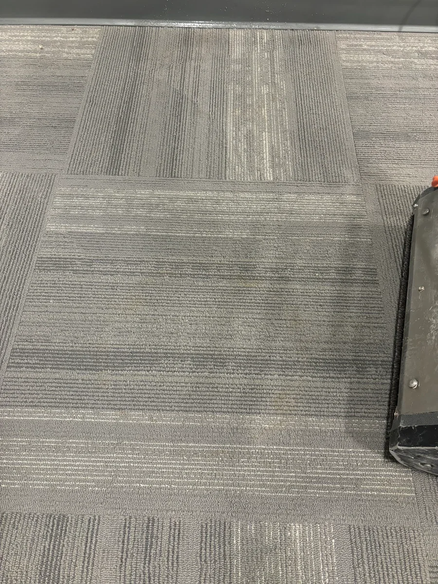 Commercial carpet cleaning on office floor tiles in a professional workspace.