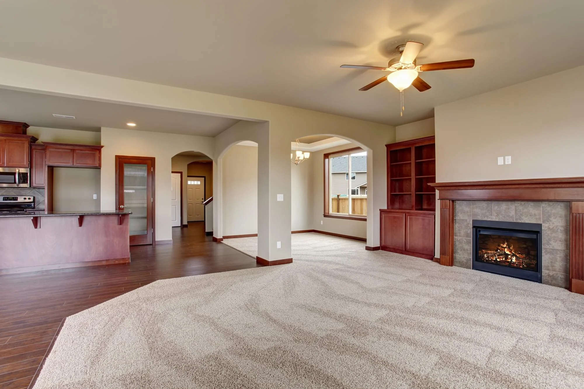 A finished residential room after cleaning services, showing a spacious open-concept living area with kitchen, fireplace, and carpet.