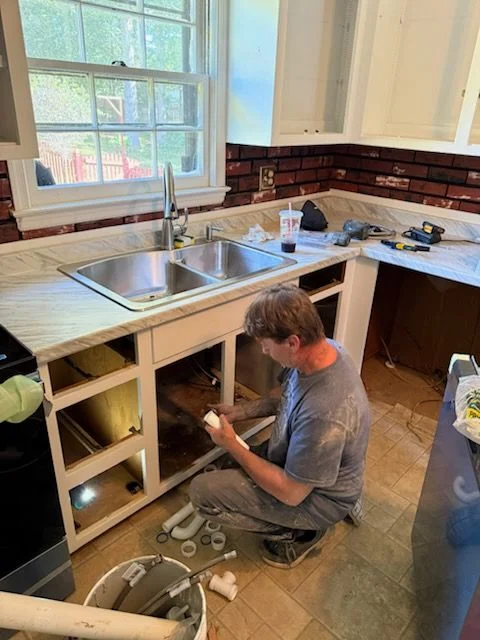 Kitchen sink and cabinet installation work being performed during a kitchen remodel renovation.
